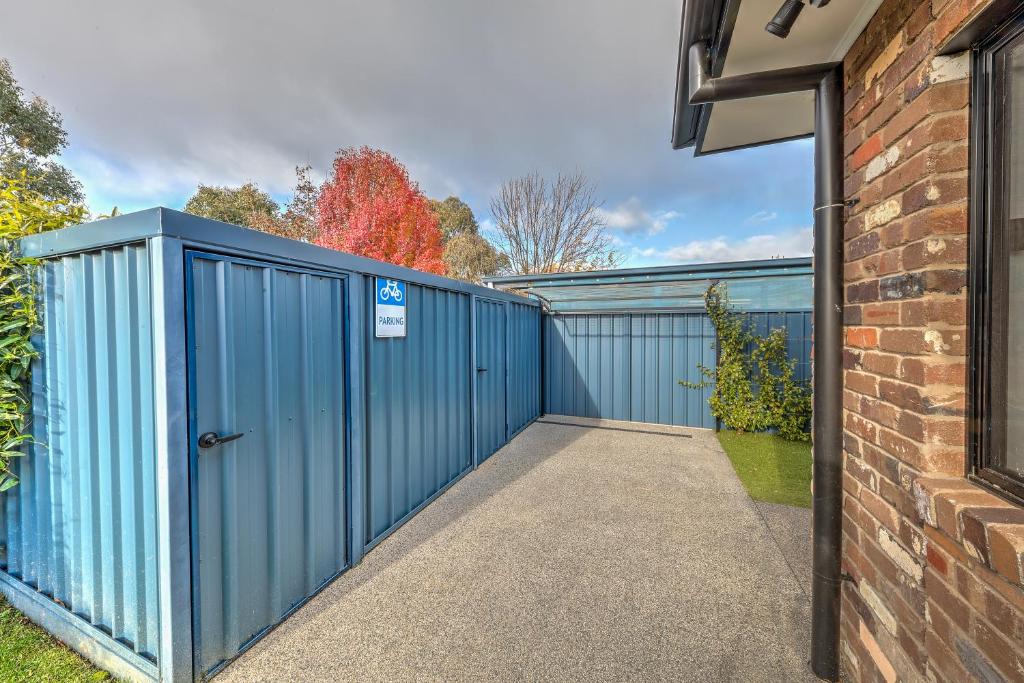 a blue fence with a gate next to a brick building at Velo Station in Porepunkah