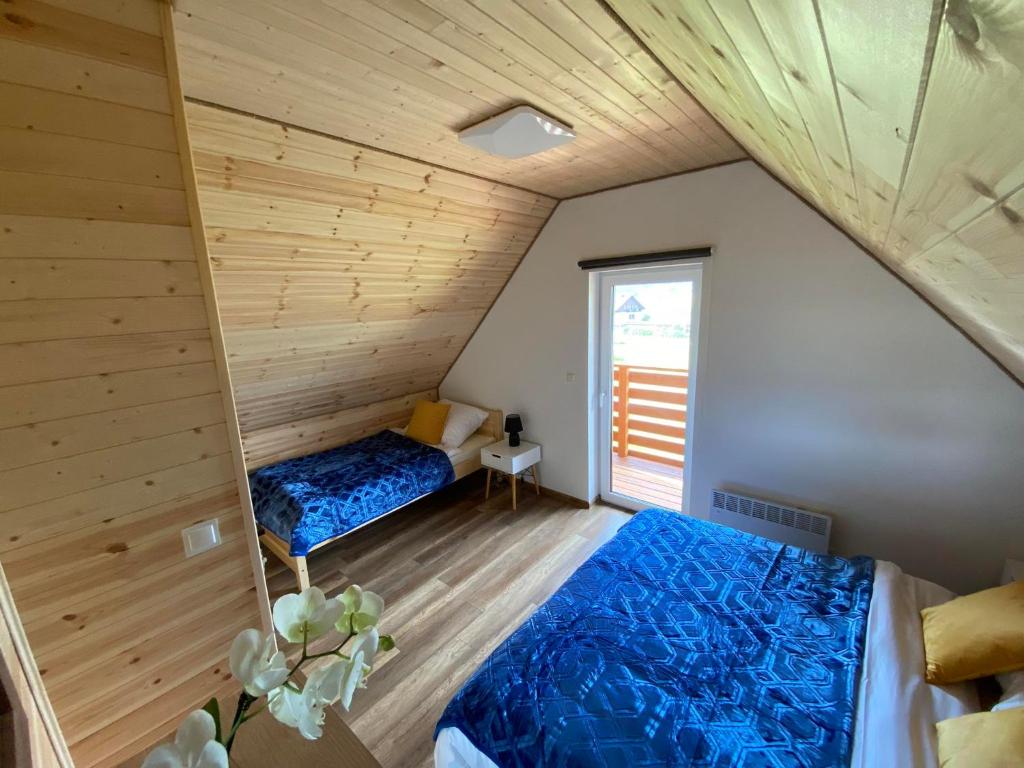 two beds in a room with a wooden ceiling at Zielony Zakątek Lasówka in Lasowka