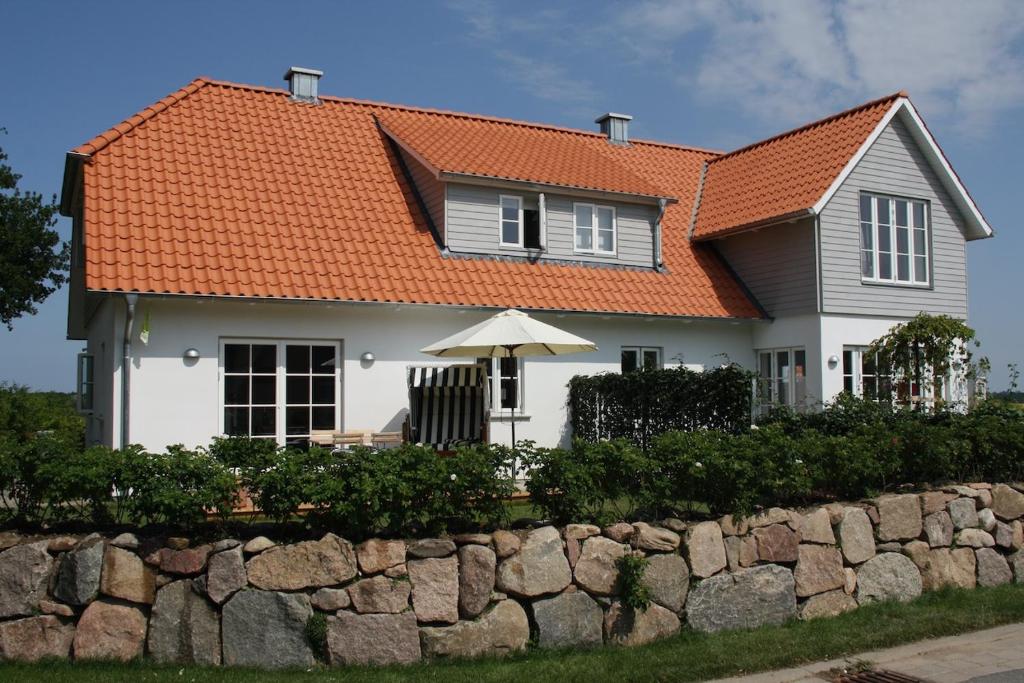 a white house with an orange roof and a stone wall at Sealounge in Dassow