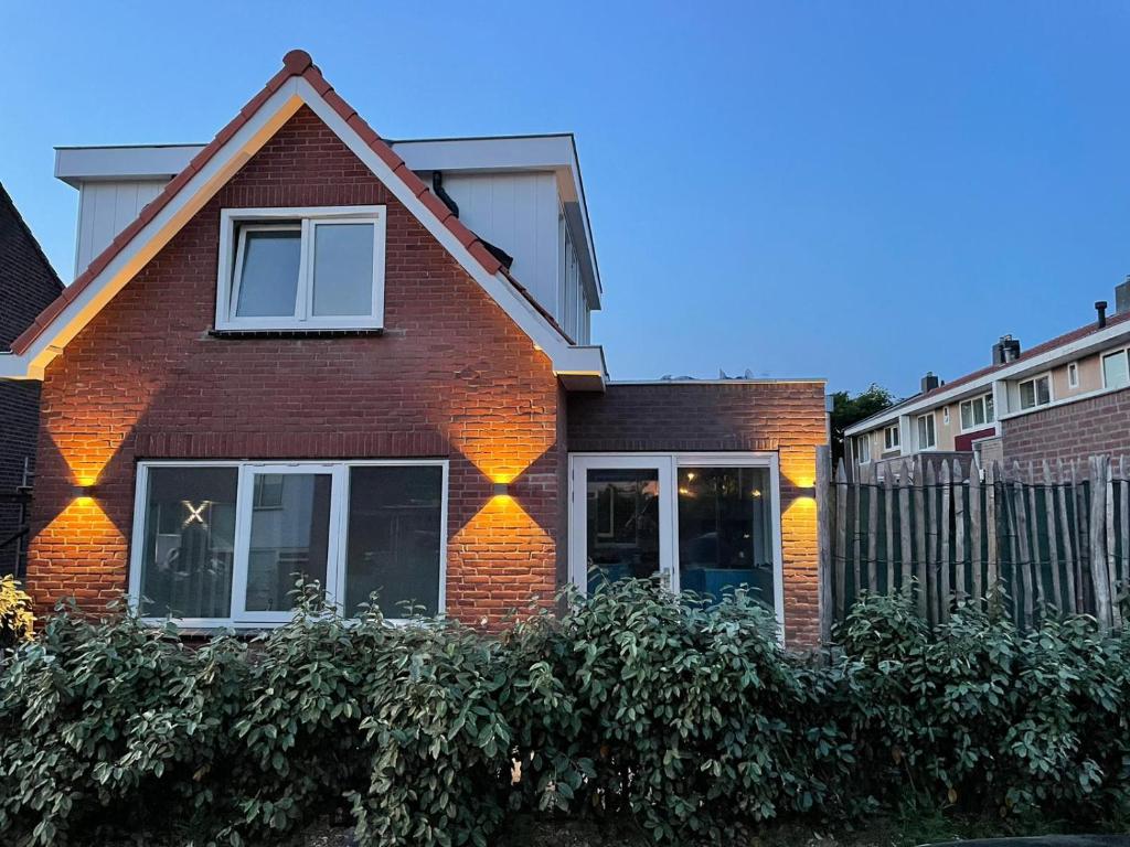 une maison en briques rouges avec des fenêtres et une clôture dans l'établissement Paris Plage - volledig vernieuwd, free parking, à Noordwijk aan Zee