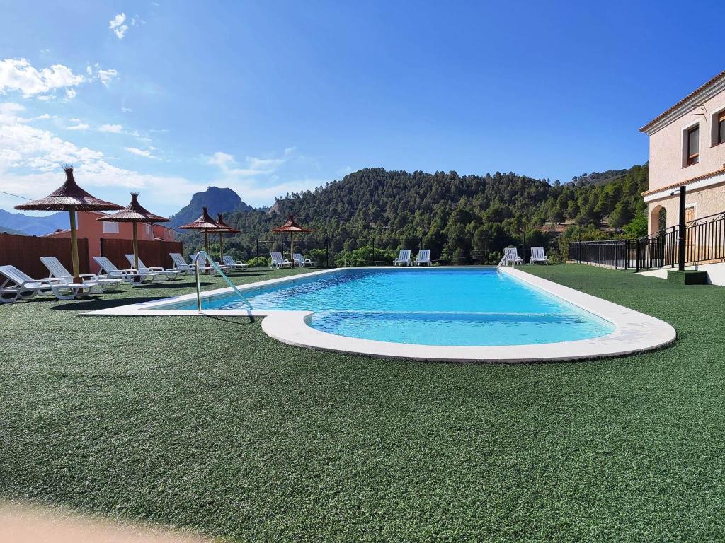 una piscina en un patio con sillas y un edificio en Casa Rural Puente Del Segura, en Elche de la Sierra