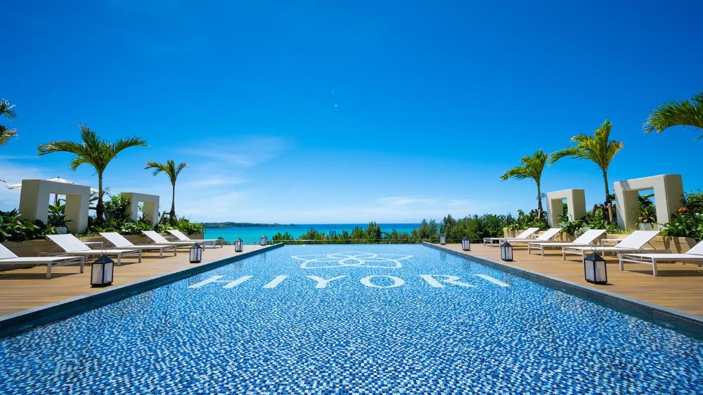 恩納村にあるHIYORIオーシャンリゾート沖縄のリゾートのスイミングプール(ラウンジチェア付)と海を望む客室です。