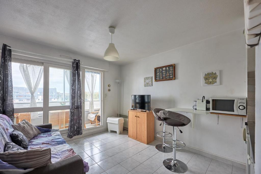 un salon avec un canapé et une cuisine dans l'établissement Galys - Appt à 1 km de la plage, à Courseulles-sur-Mer