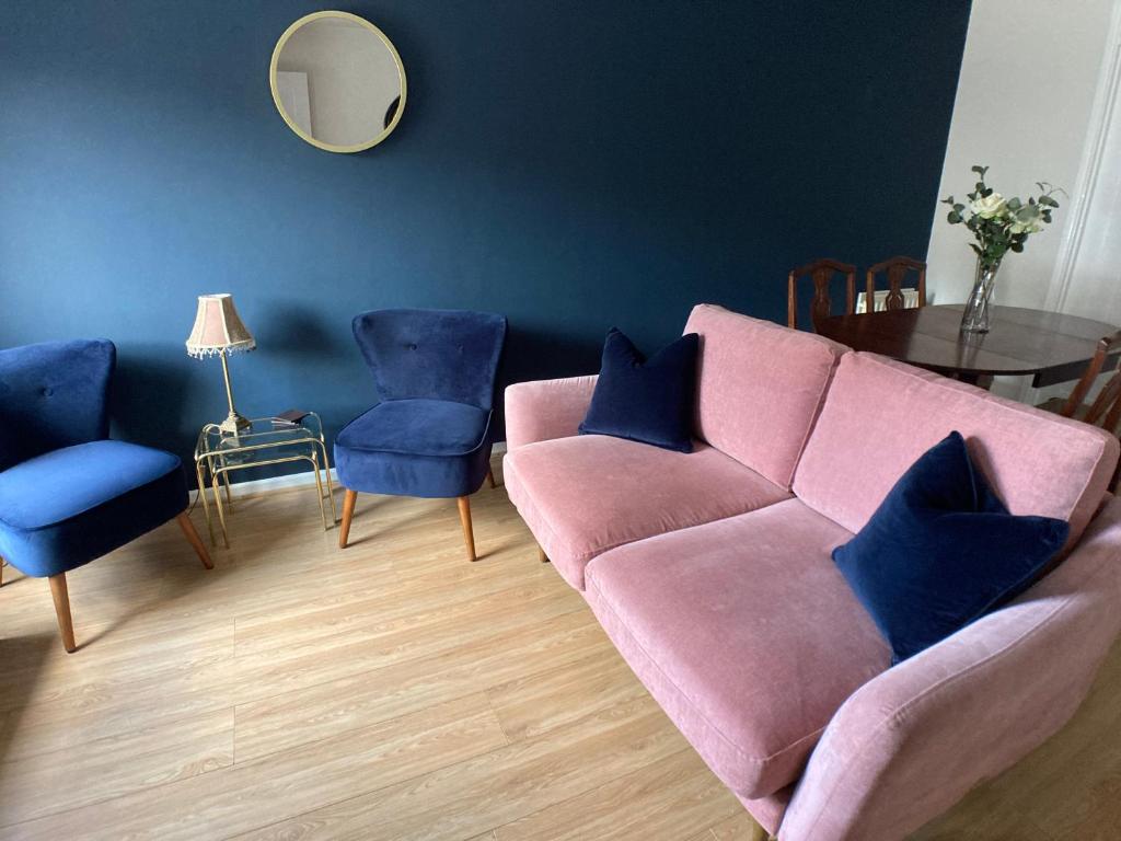 - un salon avec un canapé rose et des fauteuils bleus dans l'établissement Erin Way Apartments, à Belfast