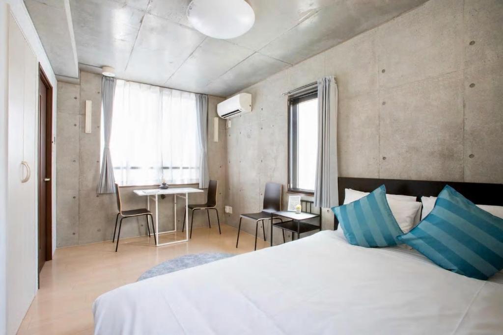 1 dormitorio con cama blanca y mesa con sillas en Laffitte Tokyo, en Tokio