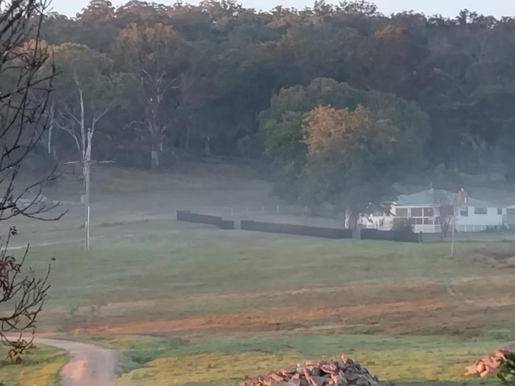 Galah Cottage Stanthorpe في Dalveen: اطلالة على ميدان فيه بيت في الخلفية