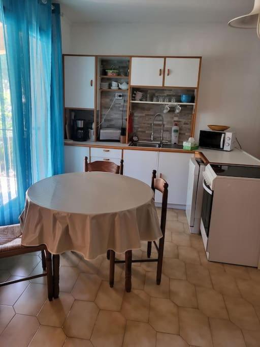 a kitchen with a table and a kitchen with a table and chairs at Rez de villa tout confort in Furiani
