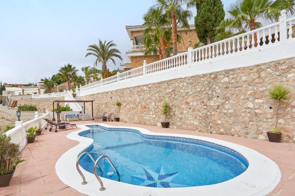 a swimming pool in front of a building with a stone wall at Villa Soraida in Ítrabo
