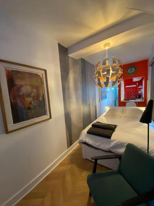 - une chambre avec un lit, une chaise et un lustre dans l'établissement Rouen galerie 112, à Rouen