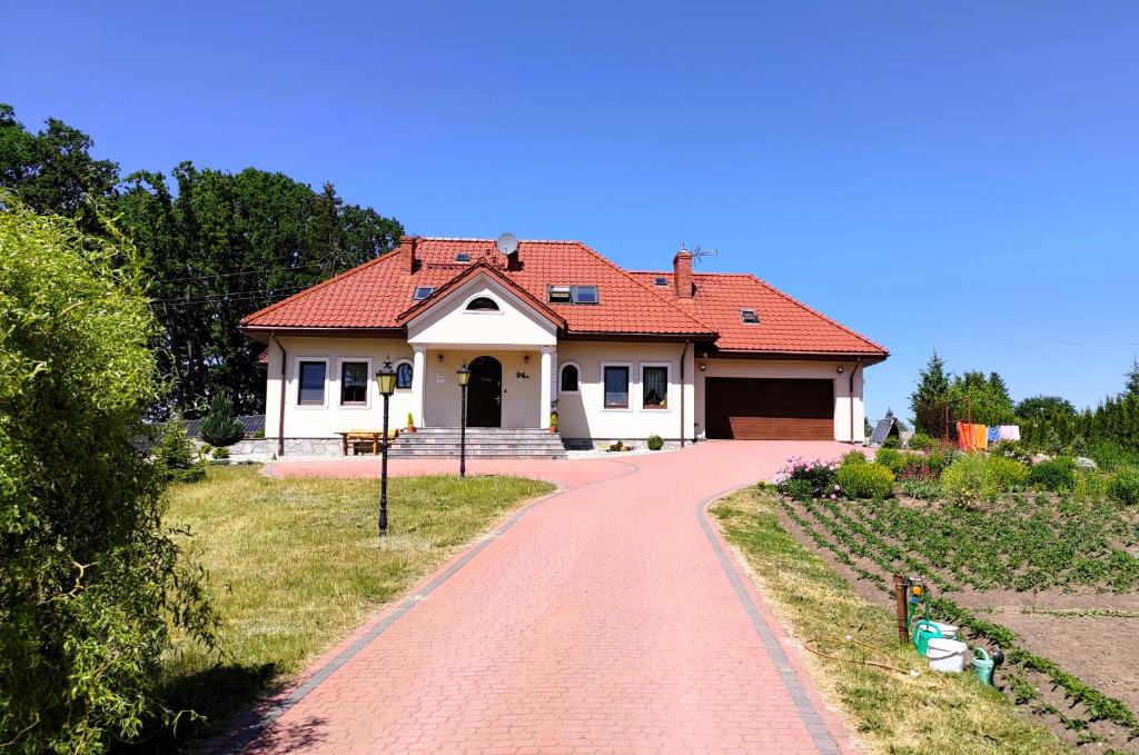 Casa blanca con techo rojo y entrada en Agroturystyka Pokój na Skarpie, en Kowale Oleckie