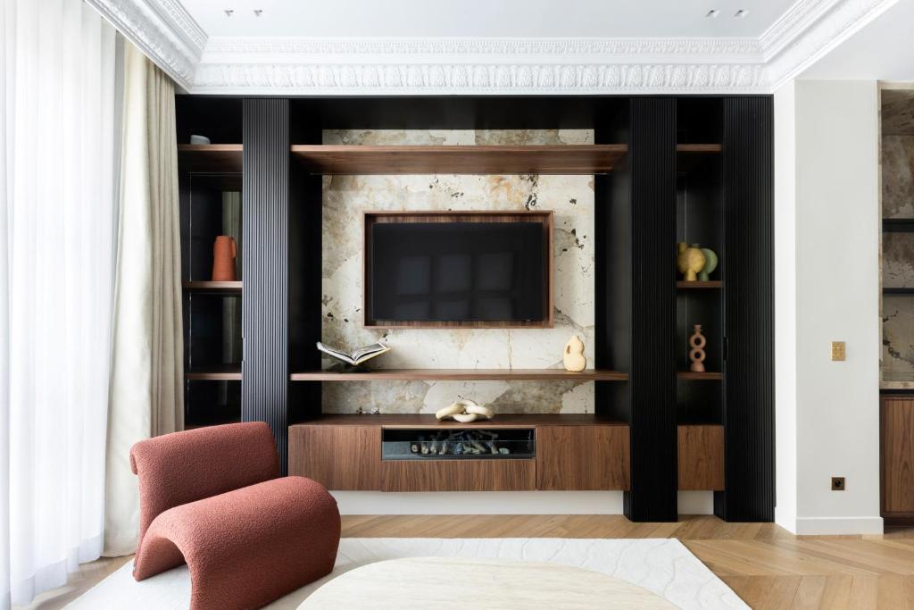 ein Wohnzimmer mit einem TV und einem roten Stuhl in der Unterkunft HIGHSTAY - Luxury Serviced Apartments - Le Marais District in Paris