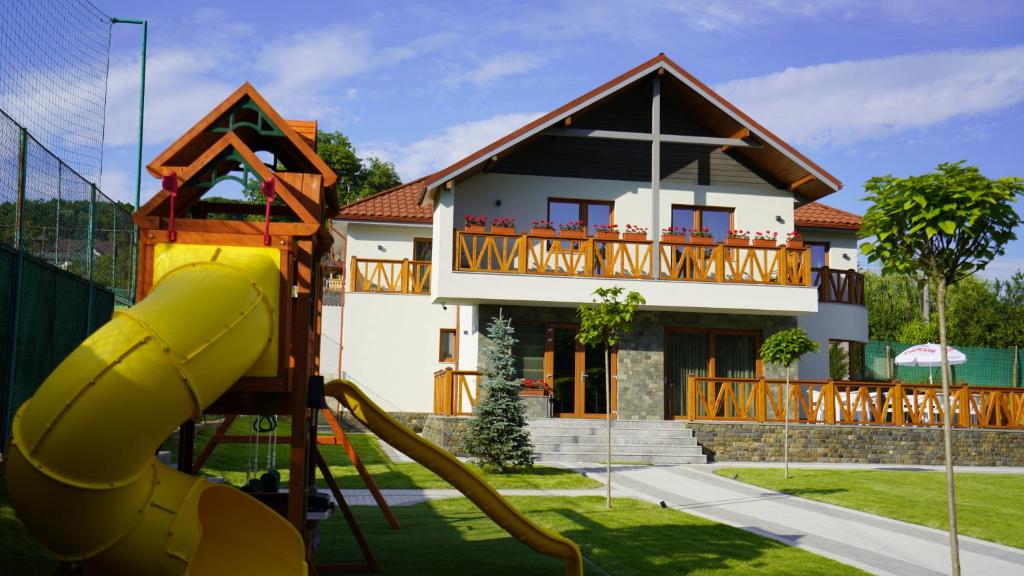 una casa con parque infantil frente a una casa en Pensiunea Magic, en Băile Govora