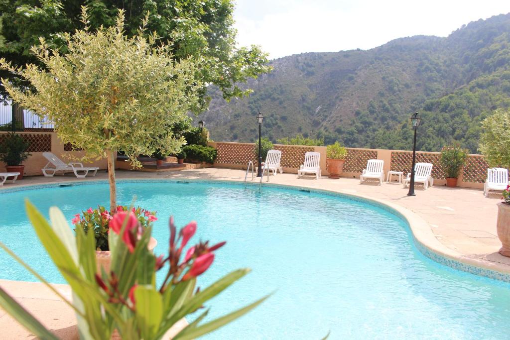 - une piscine avec des chaises, un arbre et des montagnes dans l'établissement Le BELLEVUE- MARTINON, à Utelle