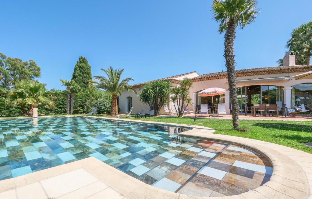 a swimming pool in front of a house with palm trees at Villa Alizée B&B in Saint-Tropez