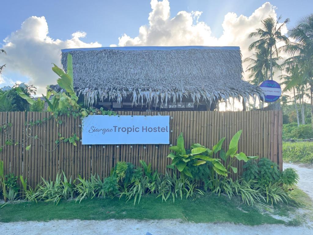 ein Schild für ein tropisches Haus vor einem Zaun in der Unterkunft Siargao Tropic Hostel in General Luna