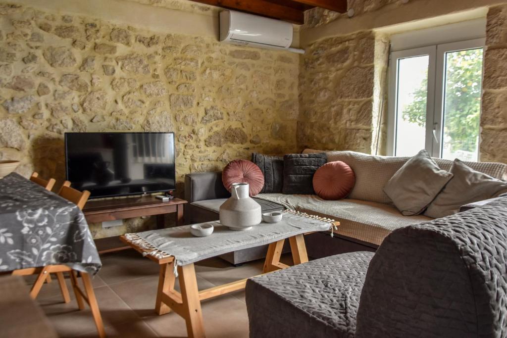 a living room with a couch and a tv at Maria's cottage house in Aïtánia