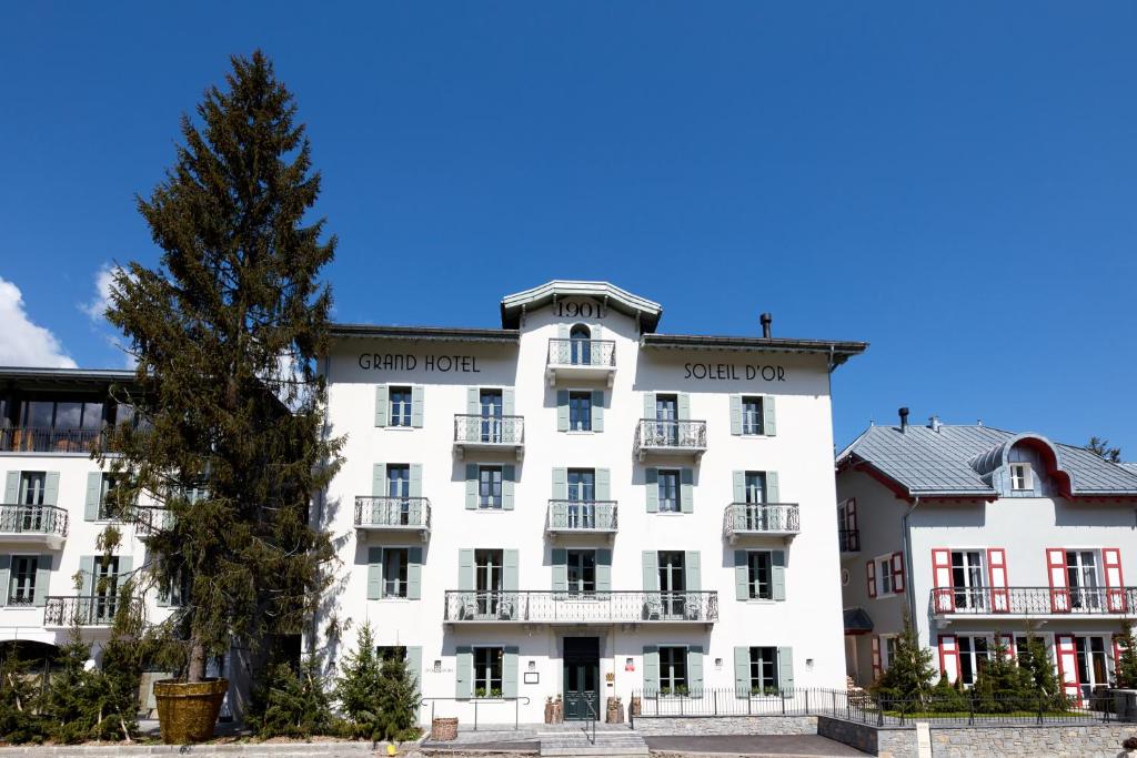ein weißes Gebäude mit einem Baum davor in der Unterkunft Grand Hotel Soleil d'Or in Megève