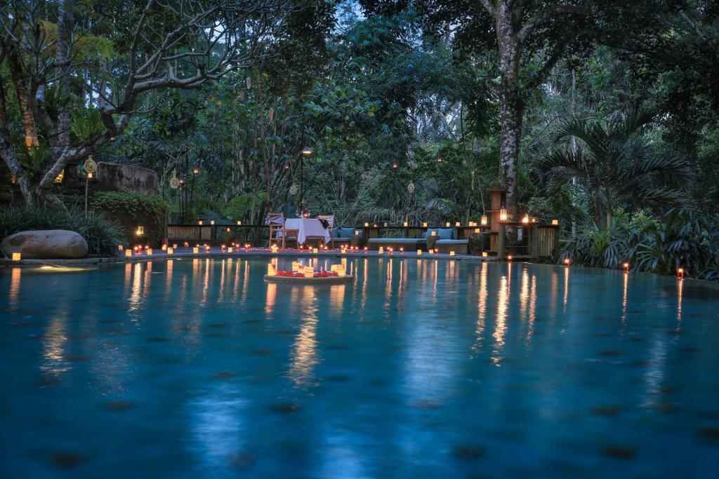 una piscina por la noche con luces en el agua en Pramana Giri Kusuma, en Payangan