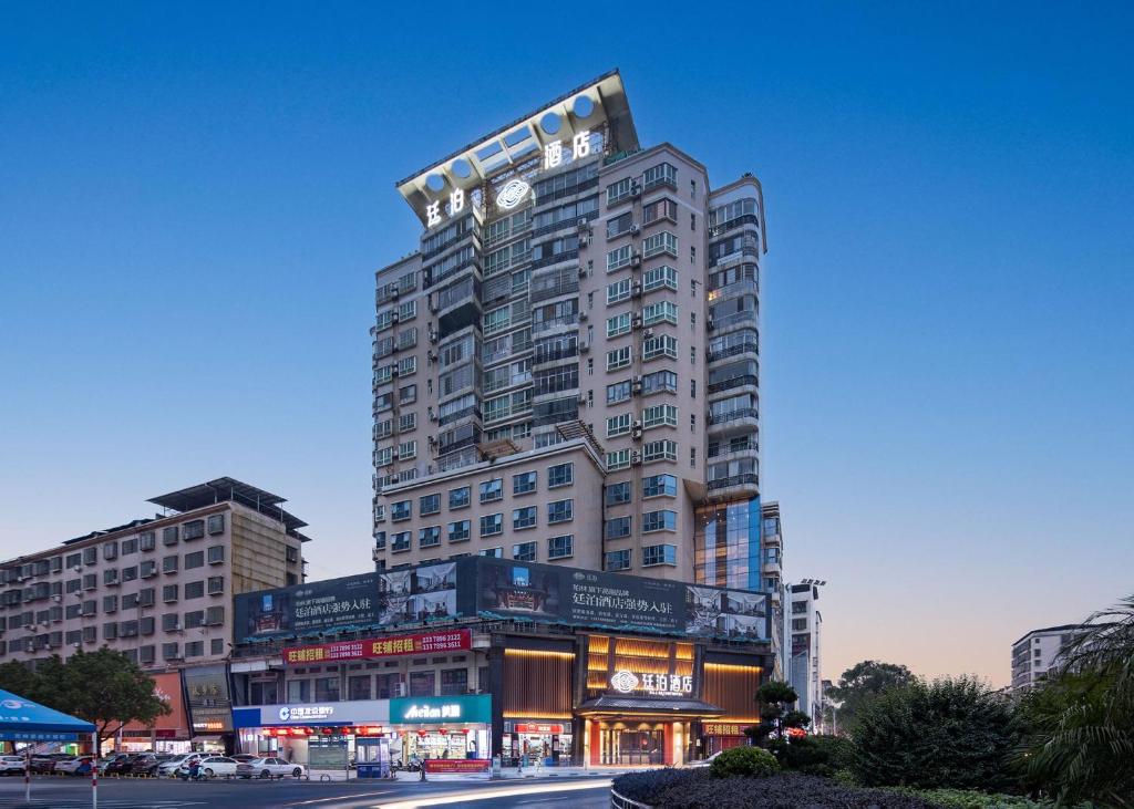 un edificio alto con un reloj encima en Till Bright Hotel, Yongzhou High -speed Railway Station, en Guzhuting