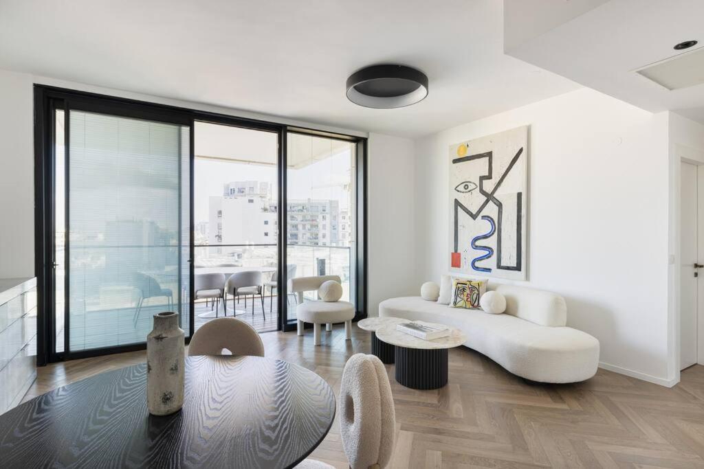 sala de estar con muebles blancos y ventana grande en Art and Luxe, en Tel Aviv