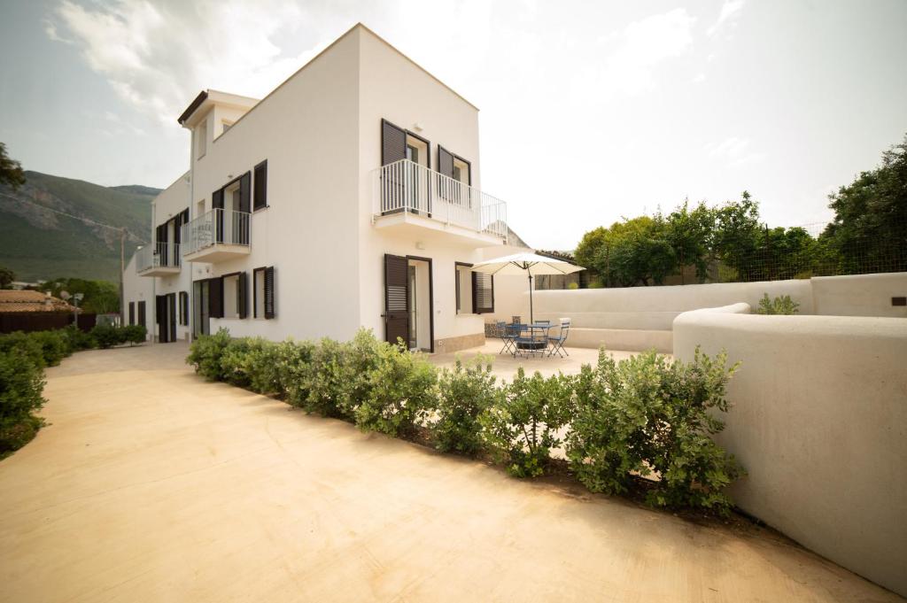 ein weißes Haus mit einer Terrasse und einem Hof in der Unterkunft Blu Home Scopello in Castellammare del Golfo