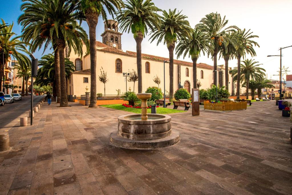 un patio con palmeras y un edificio con una fuente en Sweet Laguna Home with FREE PARKING en La Laguna