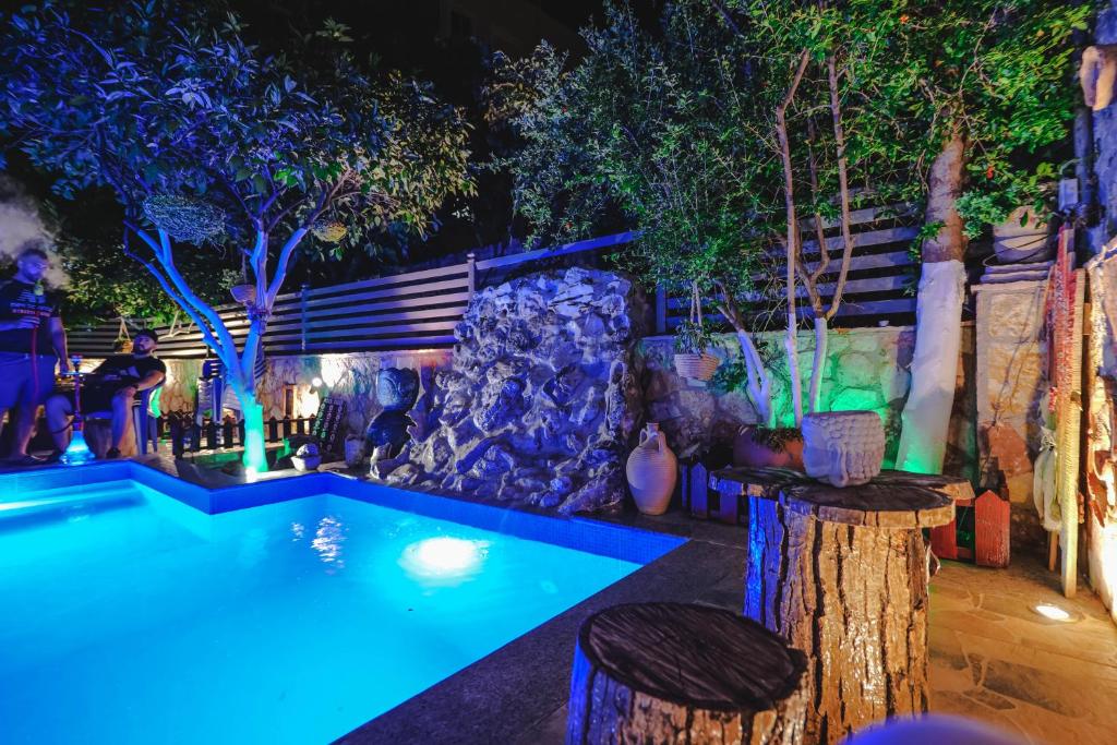 a swimming pool at night with a rock and trees at Vila Ahmeti in Sarandë
