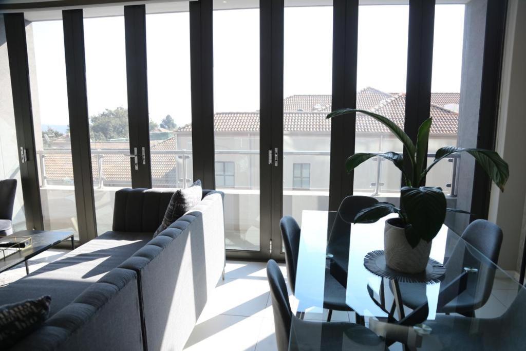 ein Wohnzimmer mit einem Sofa und einer Topfpflanze in der Unterkunft Executive 3 bed apartment with balcony & Executive 2 bed apartment in Sandton in Johannesburg