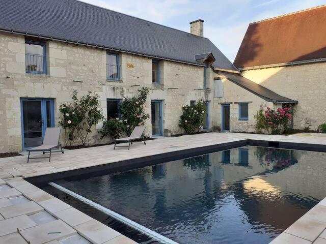 - une piscine avec 2 chaises en face d'un bâtiment dans l'établissement Logis de charme en Touraine, à Sainte-Maure-de-Touraine