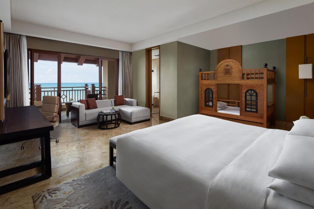 a bedroom with a large bed and a living room at Haikou Marriott Hotel in Haikou