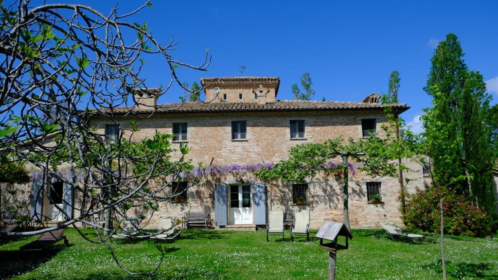 une vieille maison en pierre avec des fleurs violettes dans la cour dans l'établissement Il Casale del Duca, à Urbino