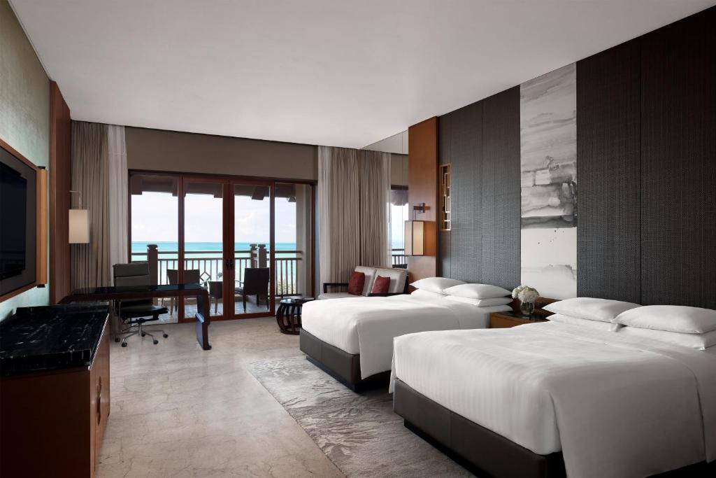 a hotel room with two beds and a desk at Haikou Marriott Hotel in Haikou