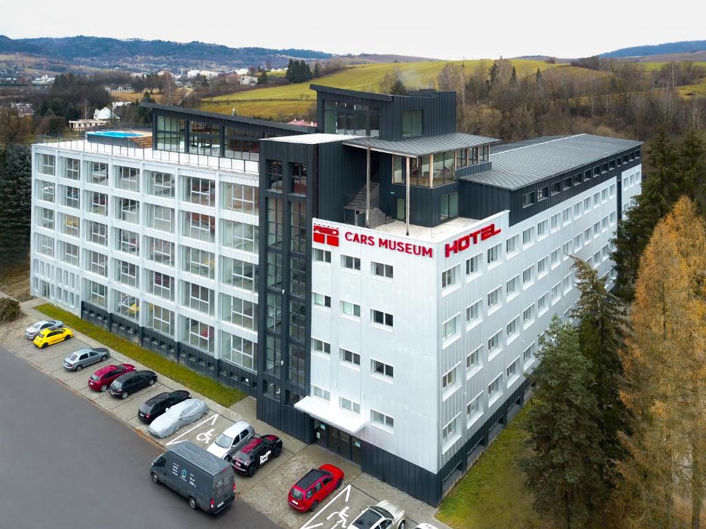 a white building with cars parked in a parking lot at HOTEL DOUBLE RED CARS Museum in Brezno