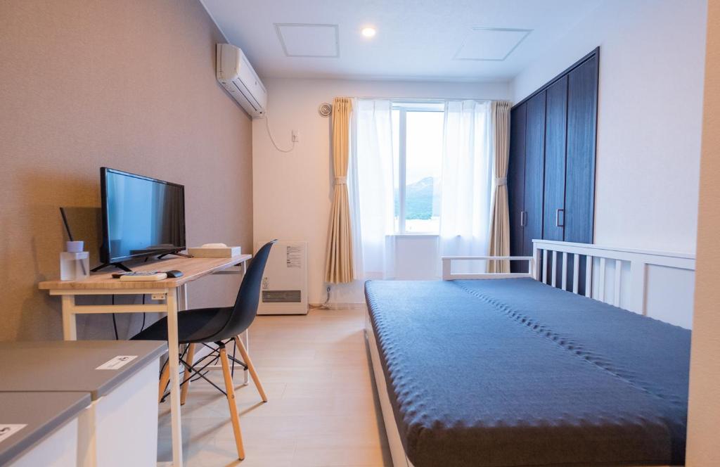 a room with a bed and a desk with a computer at Niseko Hirafu Ski Resort Condo in Kutchan