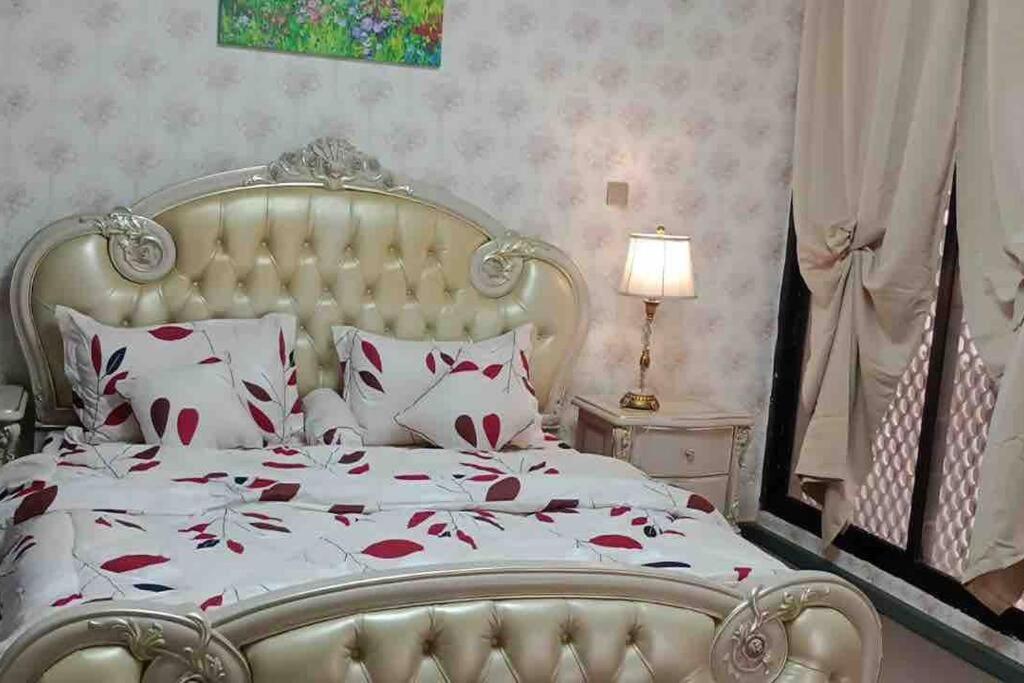a bedroom with a white bed with red flowers on it at Master Bed Room with Balcony Shared Apartment AUH UAE in Abu Dhabi