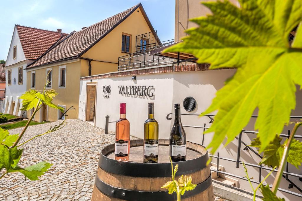 drei Flaschen Wein auf einem Fass vor einem Gebäude in der Unterkunft Resort Valtberg Valtice in Valtice