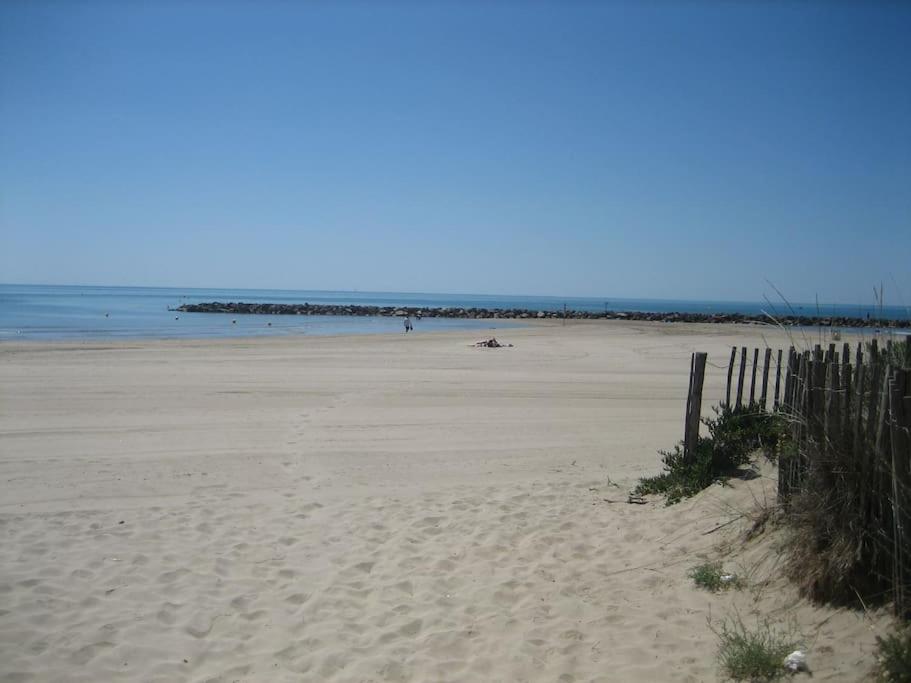 une plage de sable avec une clôture et l'océan dans l'établissement Villa climatisée proche mer Carnon Pérols, à Pérols