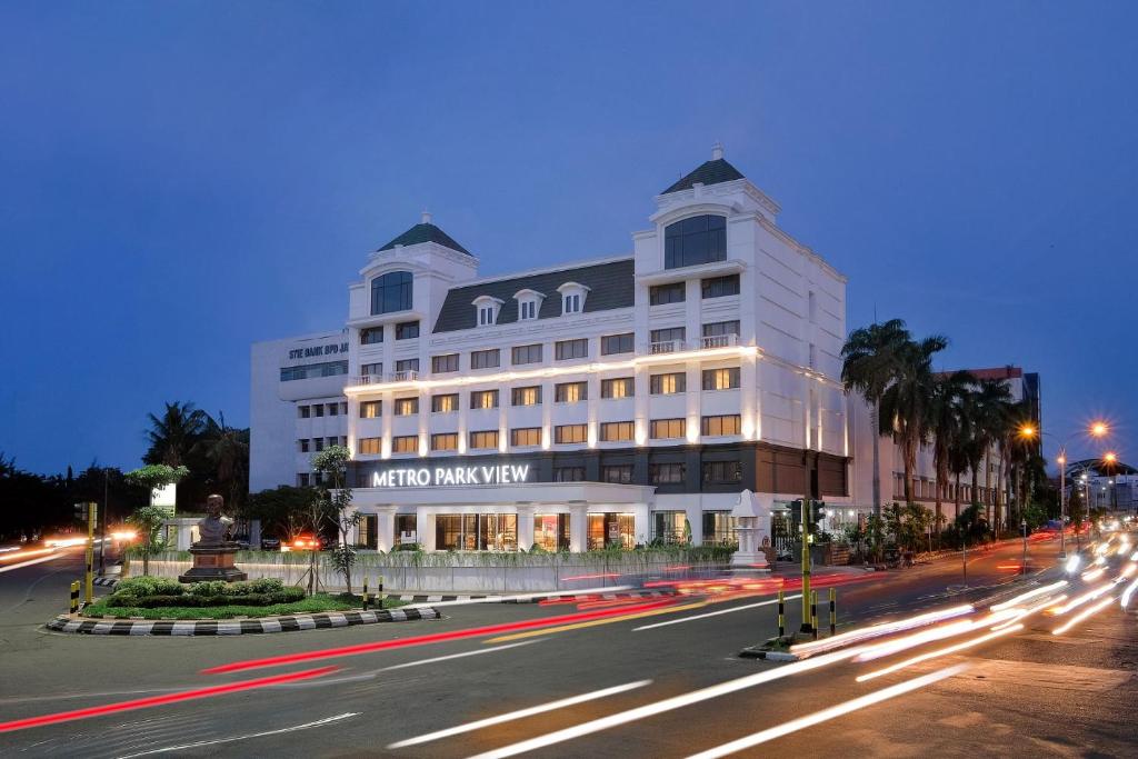 un gran edificio blanco en una calle de la ciudad por la noche en Metro Park View Hotel Kota Lama Semarang, en Semarang