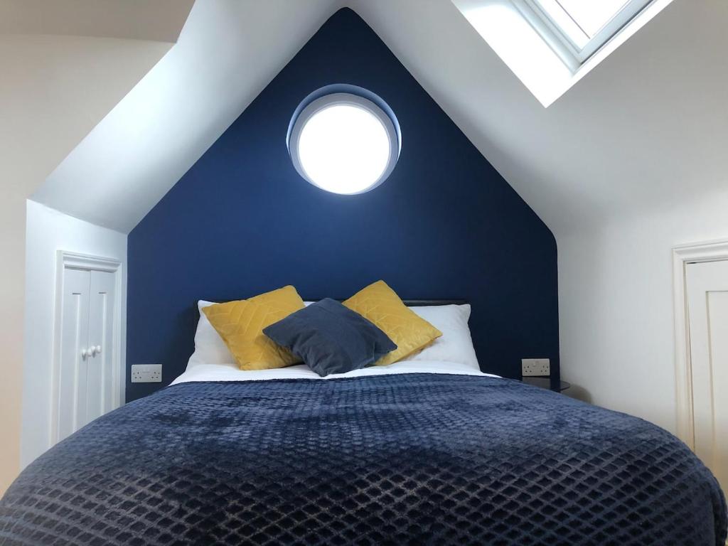 a blue bedroom with a bed with a round window at Cosy Loft Apartment Just Off Vibrant Mill Rd Cb1 in Cambridge
