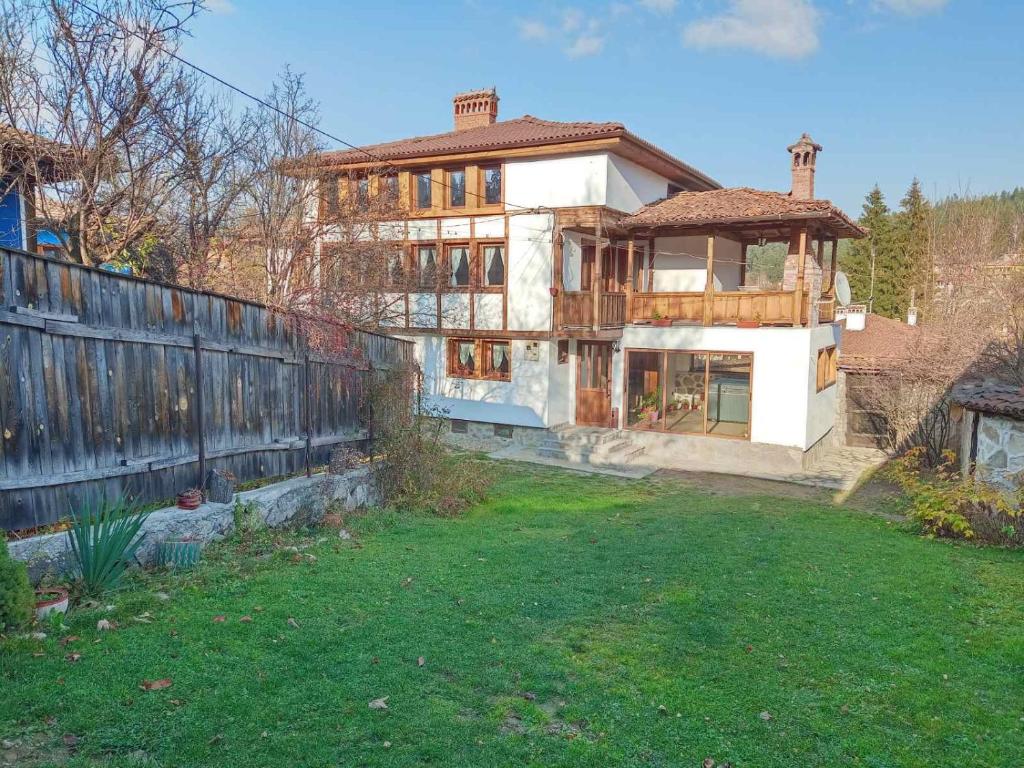 a large house with a fence and a yard at Villa Lyutovi Holiday Home in Koprivshtitsa