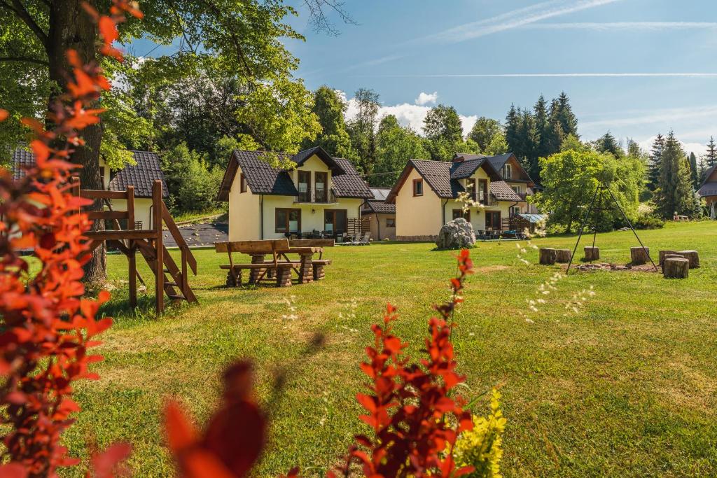 a house in a yard with red flowers in the foreground at Domki Pod Jarmutą in Szczawnica