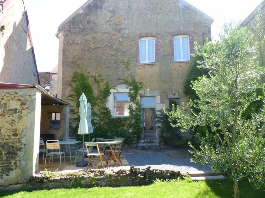 uma casa com uma mesa e cadeiras e um guarda-sol em Des Envies et Des Songes em Saint-Amand-en-Puisaye
