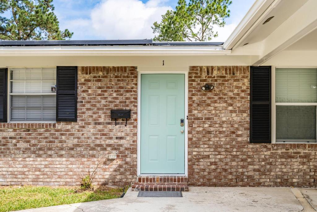 a brick house with a blue door at Jacksonville Retreat: Unwind in Style at our Cozy Duplex Apartment in Jacksonville