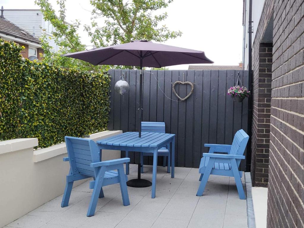 une table bleue, deux chaises et un parasol dans l'établissement Ross Mill, à Belfast