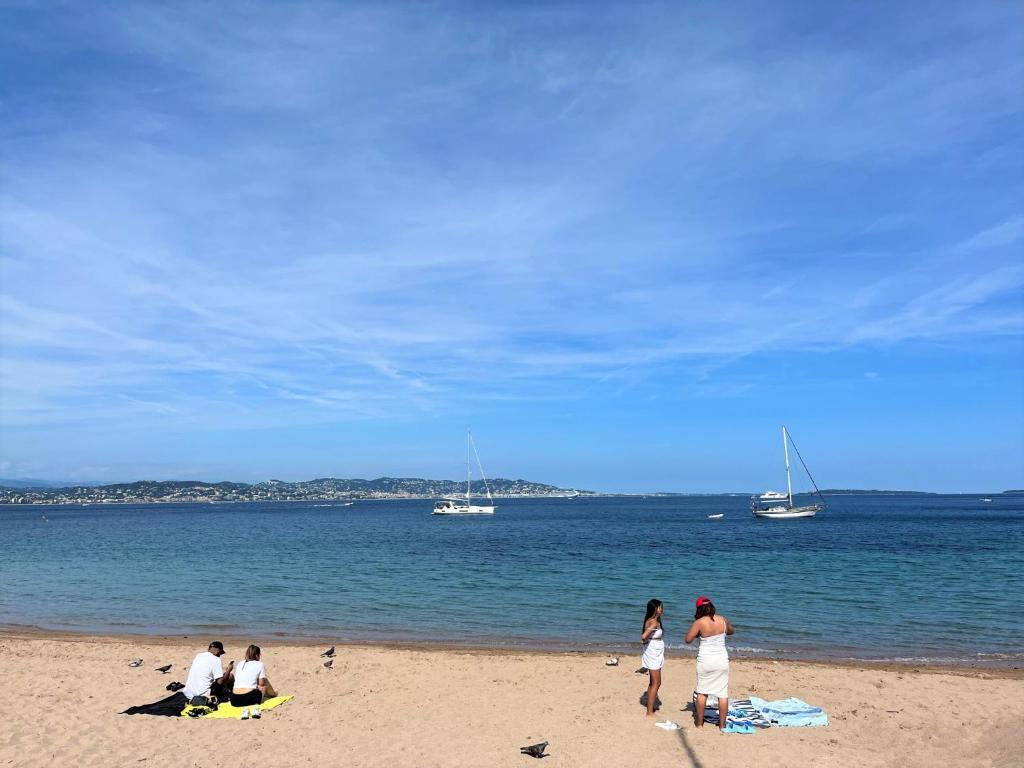 un groupe de personnes sur une plage avec des bateaux dans l'eau dans l'établissement Apartment beach acces Theoule sur mer, à Théoule-sur-Mer