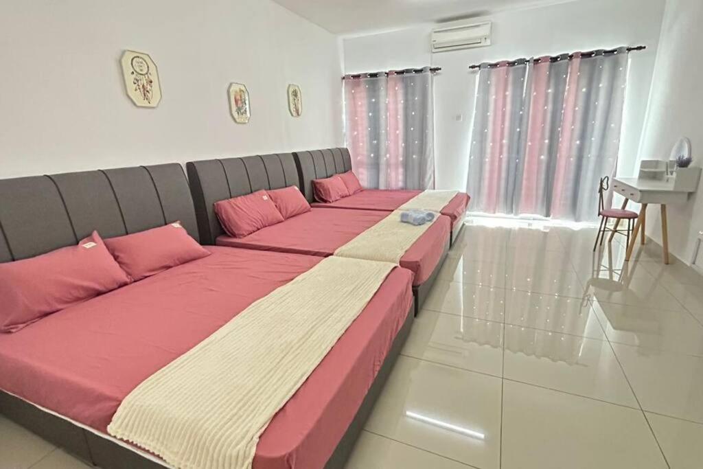 ein großes Bett mit rosa Kissen in einem Zimmer in der Unterkunft 77 Mantin # U Homestay - 4Bed & 4Bath in Mantin