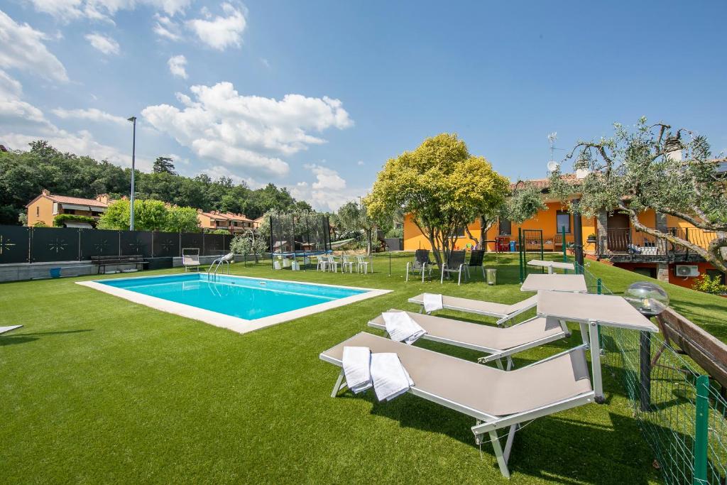 une cour avec une piscine et des chaises longues dans l'établissement Villa Teresa Apt Lake Garda View - Happy Rentals, à Soiano del Lago