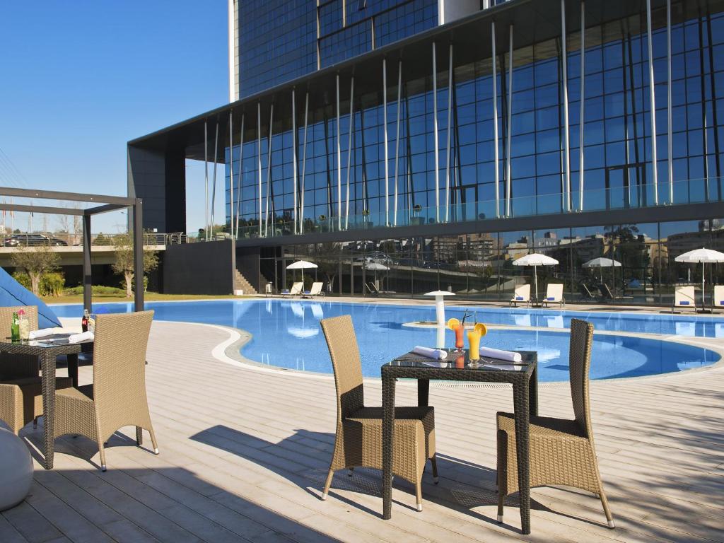 a table and chairs next to a swimming pool at Melia Braga Hotel & Spa in Braga