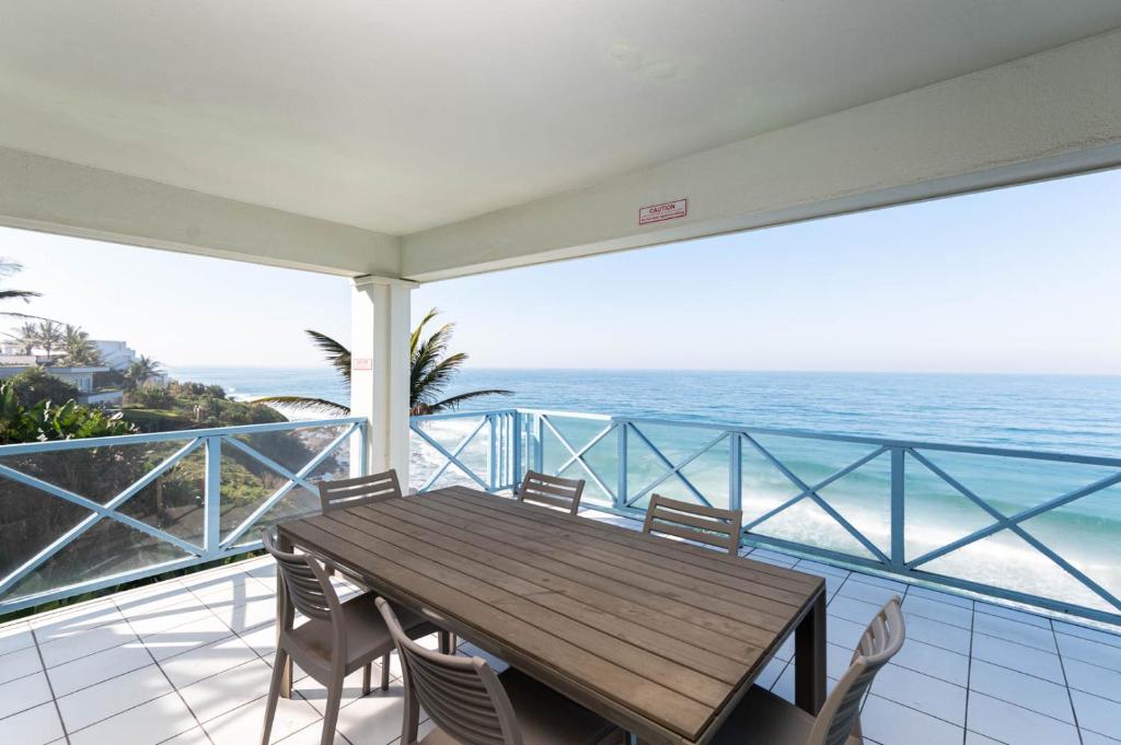 einen Esstisch und Stühle auf einem Balkon mit Meerblick in der Unterkunft The Islands 9 in Ballito