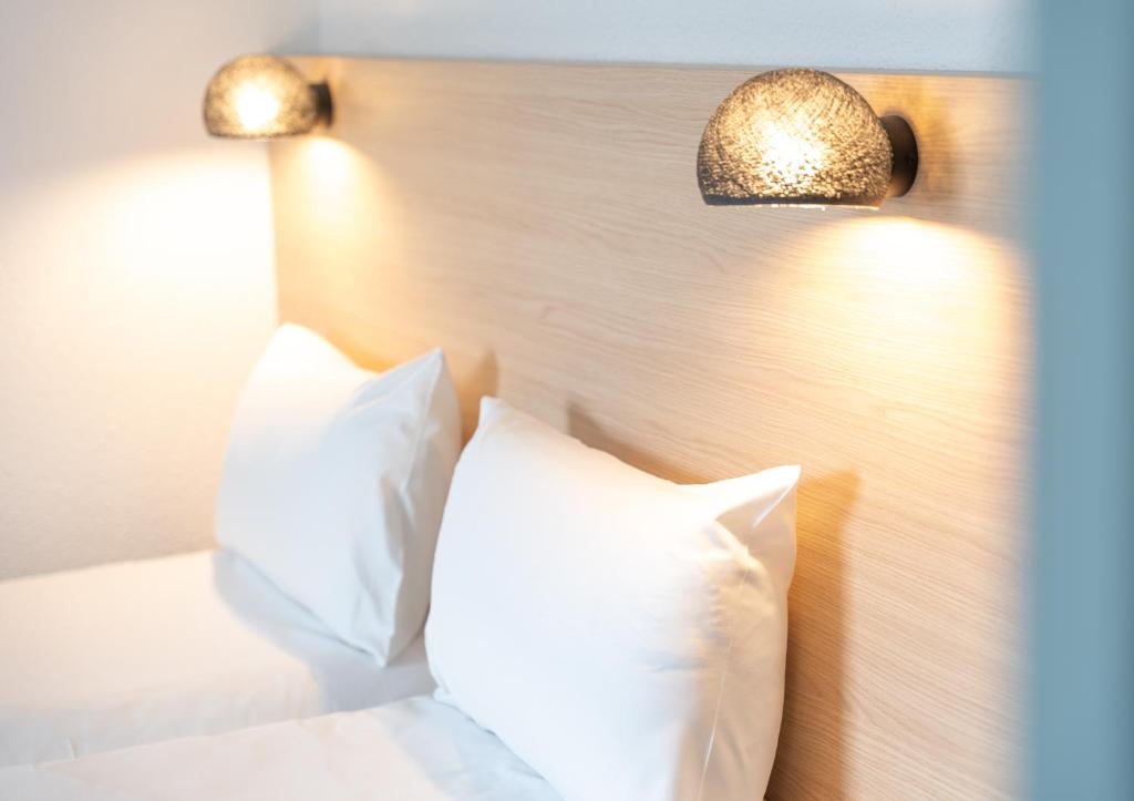a bed with white pillows and two lights on it at Hôtel Inn Design La Rochelle in La Rochelle